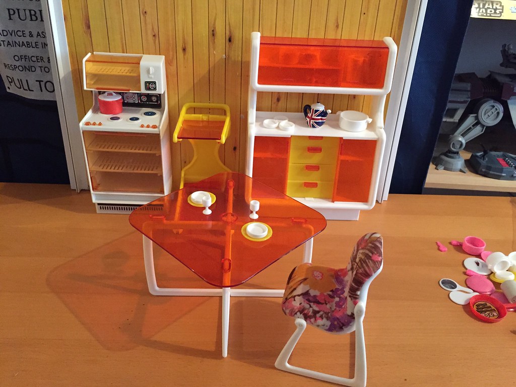 Miniature 1970s-style furniture, including an opaque red table and kitchenette